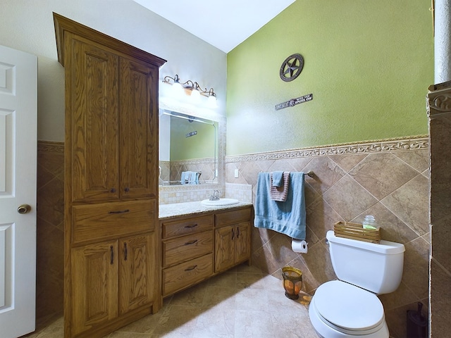 bathroom featuring toilet, tile patterned flooring, tile walls, and vanity