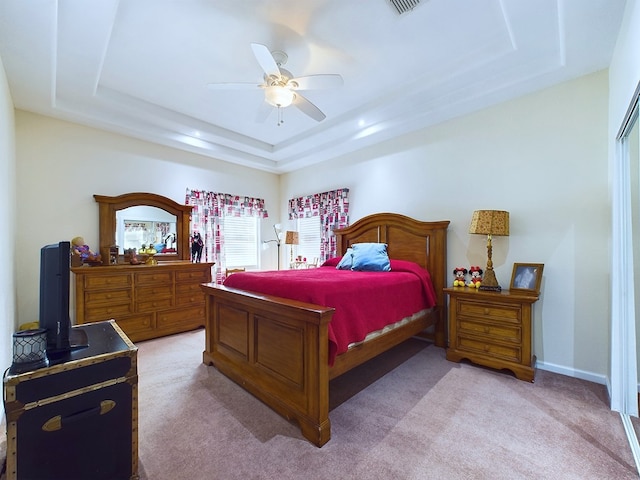 bedroom featuring a raised ceiling, ceiling fan, and light colored carpet