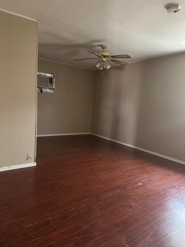 empty room with ceiling fan, a wall unit AC, and dark hardwood / wood-style flooring