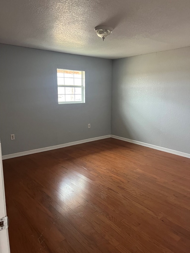 spare room with dark hardwood / wood-style flooring and a textured ceiling