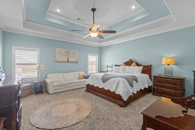 carpeted bedroom with visible vents, ceiling fan, crown molding, and a tray ceiling