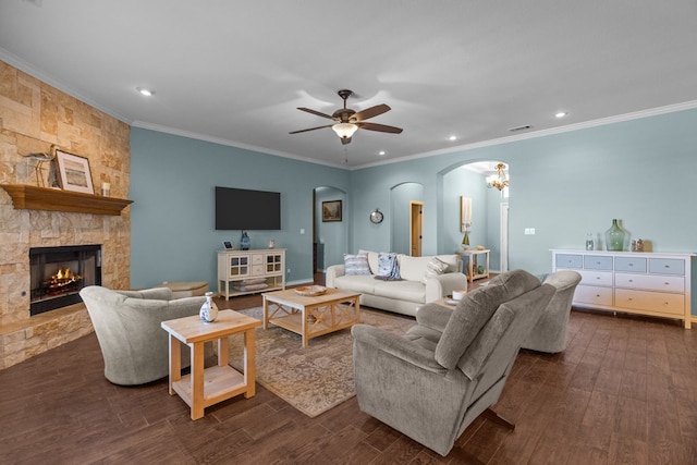 living room featuring visible vents, arched walkways, ornamental molding, a stone fireplace, and dark wood-type flooring