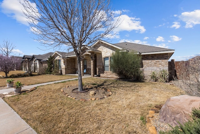 single story home with stone siding, brick siding, and a front lawn