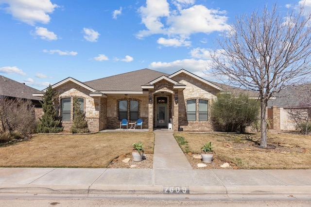 view of front of home featuring brick siding, a front yard, and roof with shingles