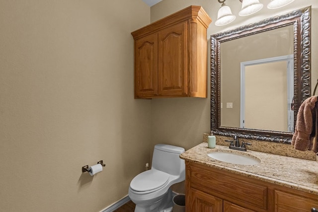 half bathroom with baseboards, toilet, and vanity