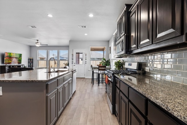 kitchen featuring stainless steel appliances, a sink, visible vents, and decorative backsplash