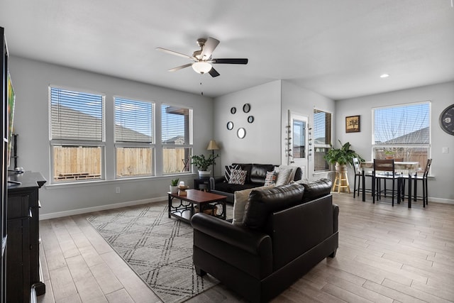 living room featuring a ceiling fan, plenty of natural light, baseboards, and wood finished floors