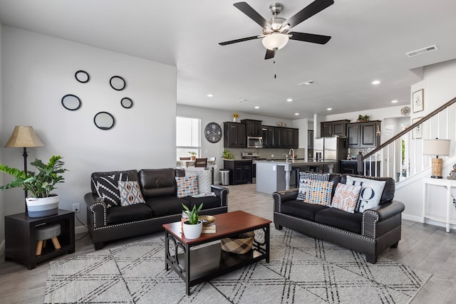 living area with recessed lighting, visible vents, a ceiling fan, stairway, and light wood finished floors