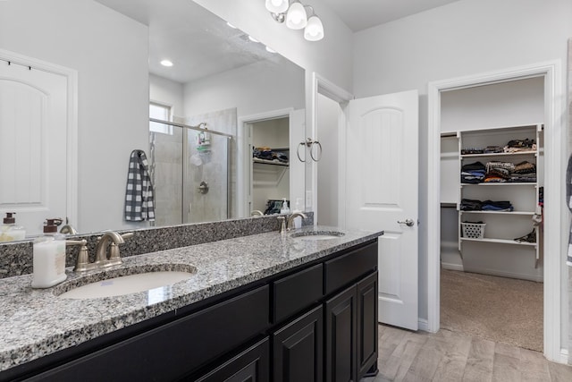 full bath featuring double vanity, a shower stall, a walk in closet, and a sink