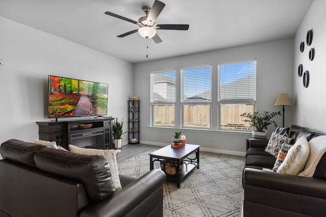 living room featuring ceiling fan, wood finished floors, and baseboards