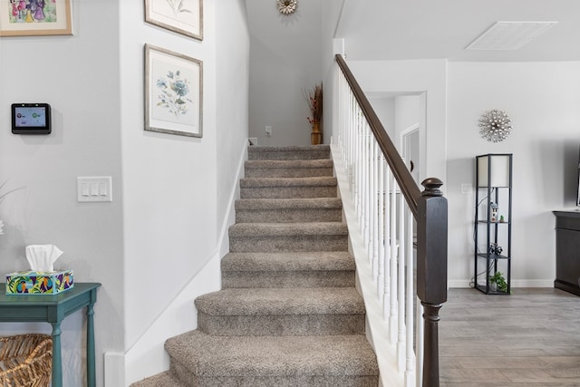 stairs with visible vents, baseboards, and wood finished floors