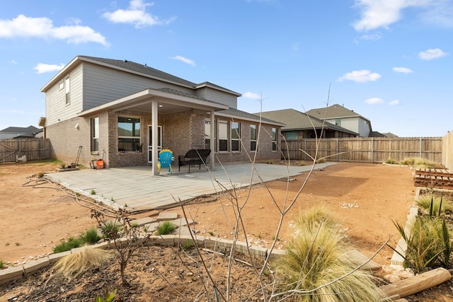 back of house with a fenced backyard, a patio, and brick siding