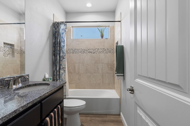 full bath with toilet, shower / bathtub combination with curtain, wood finished floors, and vanity