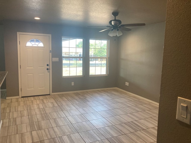 foyer entrance with ceiling fan and a textured ceiling