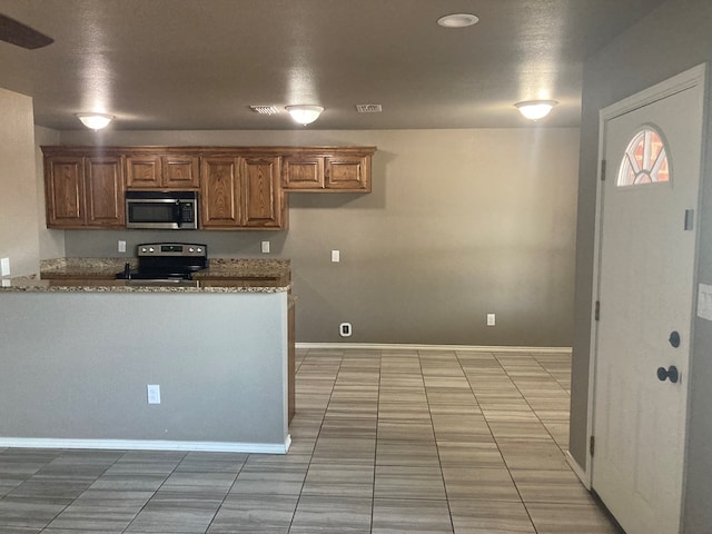 kitchen with light stone countertops, light tile patterned flooring, a textured ceiling, and appliances with stainless steel finishes