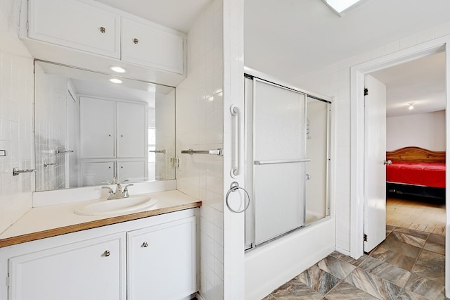 bathroom with wood-type flooring, vanity, and enclosed tub / shower combo