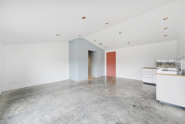 unfurnished living room with sink, concrete flooring, and lofted ceiling