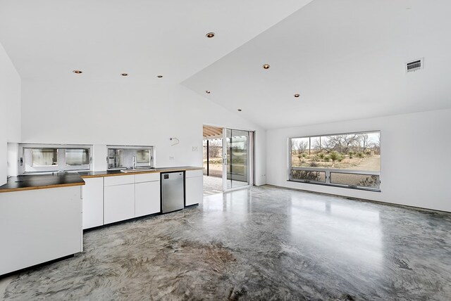 kitchen with stainless steel dishwasher, white cabinetry, sink, and high vaulted ceiling