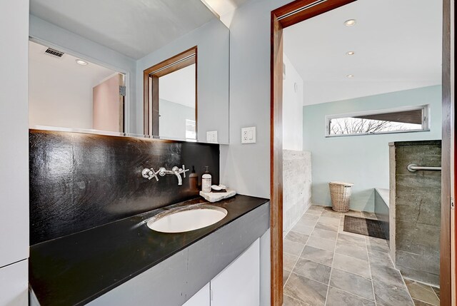 bathroom featuring tile patterned floors, vanity, lofted ceiling, and backsplash