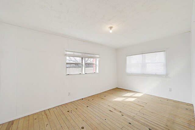 spare room featuring light hardwood / wood-style floors and a textured ceiling