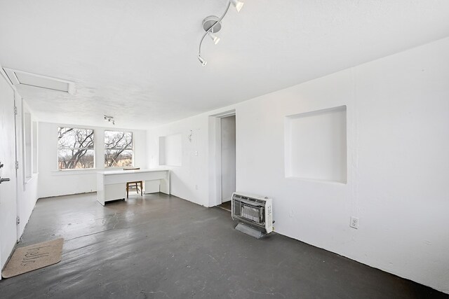 spare room featuring rail lighting, heating unit, and a wood stove