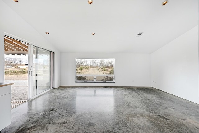 unfurnished room featuring lofted ceiling and concrete flooring