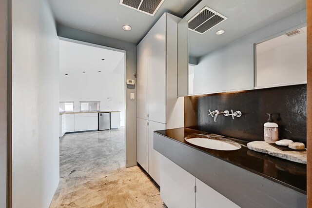 bathroom featuring decorative backsplash, concrete flooring, and sink