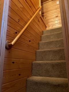 stairway featuring wooden ceiling and wooden walls