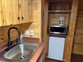 kitchen with wood walls, white appliances, and sink