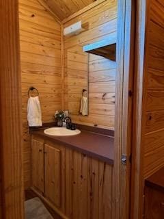 bathroom with vanity, wood walls, wood ceiling, and lofted ceiling