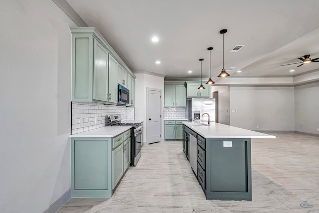 kitchen featuring decorative backsplash, appliances with stainless steel finishes, ceiling fan, a kitchen island with sink, and hanging light fixtures