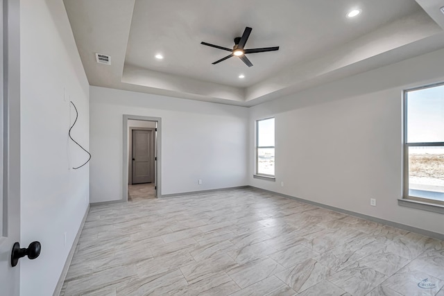 empty room with a raised ceiling and ceiling fan