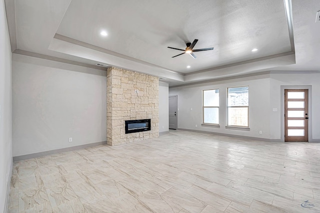 unfurnished living room with a fireplace, a raised ceiling, and ceiling fan