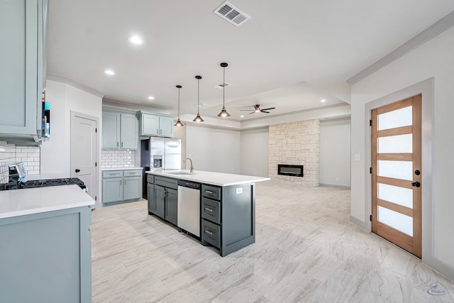 kitchen with ceiling fan, stainless steel appliances, tasteful backsplash, pendant lighting, and a kitchen island with sink