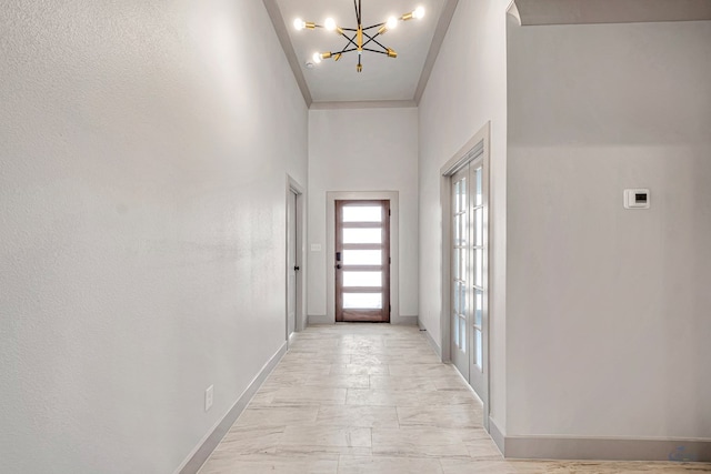 corridor featuring a towering ceiling and a chandelier