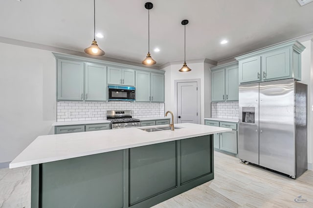 kitchen featuring backsplash, a kitchen island with sink, sink, decorative light fixtures, and stainless steel appliances