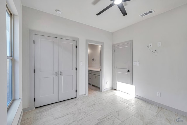 unfurnished bedroom featuring ceiling fan, a closet, ensuite bathroom, and multiple windows