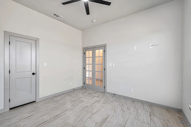 empty room featuring ceiling fan and french doors