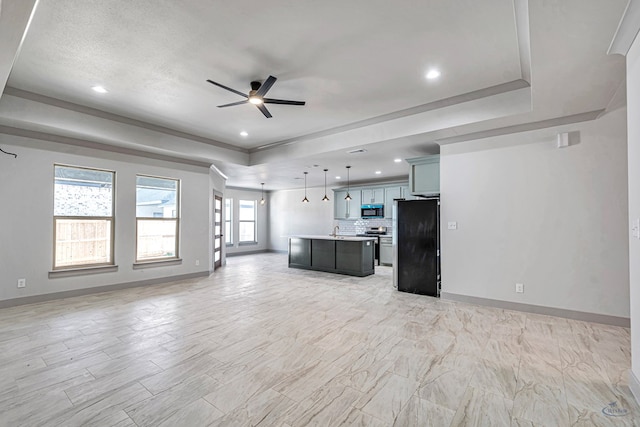 unfurnished living room featuring ceiling fan and a tray ceiling