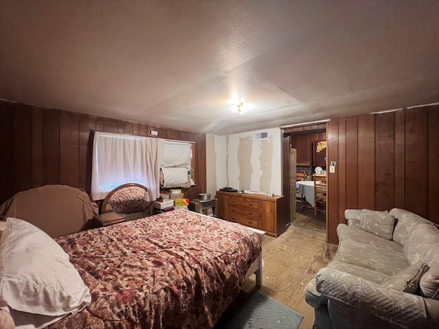 bedroom with light hardwood / wood-style flooring and wooden walls