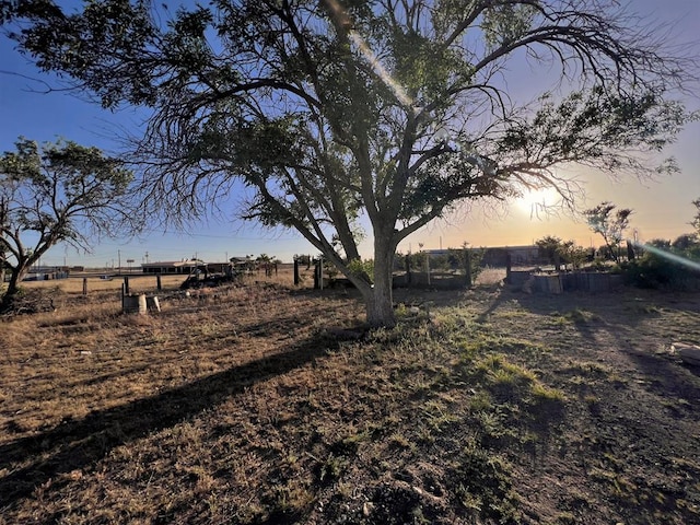 yard at dusk featuring a rural view