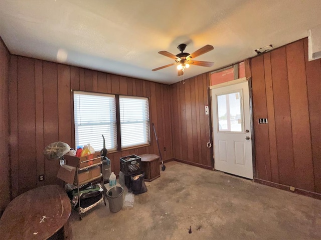 foyer entrance with ceiling fan and wood walls