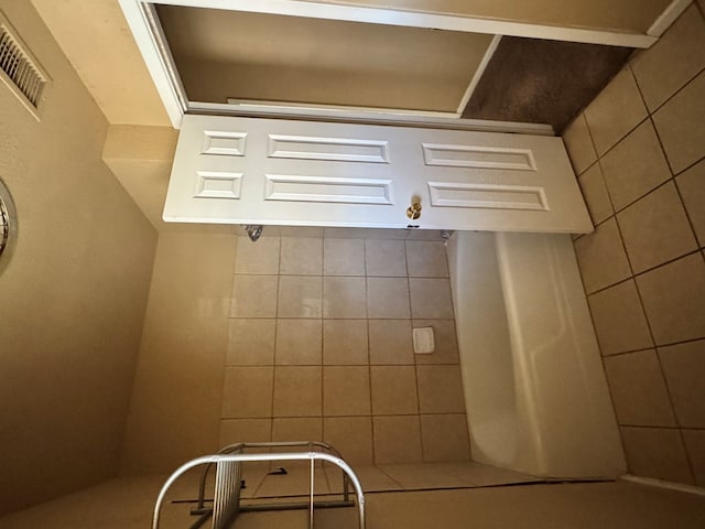 bathroom with visible vents and tile walls