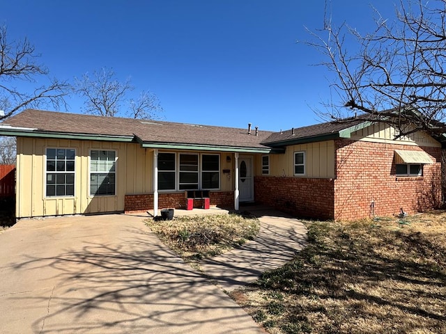 single story home with covered porch, brick siding, and board and batten siding