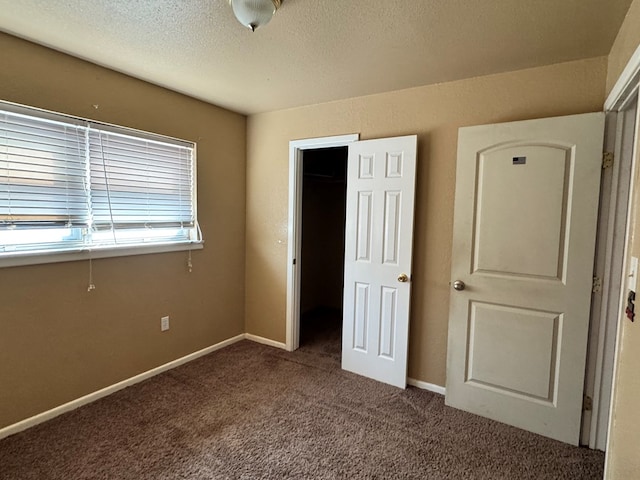 unfurnished bedroom with carpet, baseboards, and a textured ceiling