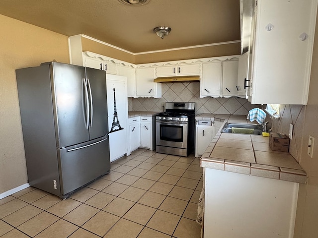 kitchen with light tile patterned floors, tasteful backsplash, stainless steel appliances, under cabinet range hood, and a sink