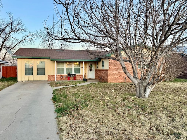 ranch-style home with driveway, fence, board and batten siding, and brick siding