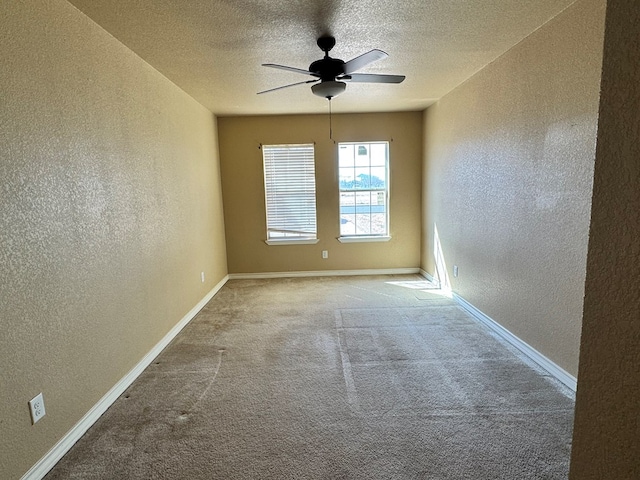 empty room with a textured ceiling, a textured wall, carpet flooring, and baseboards