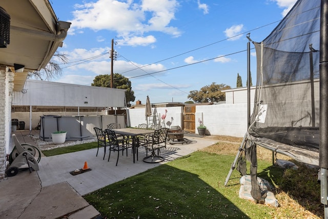 view of yard featuring a patio, a fenced backyard, a fire pit, a fenced in pool, and a trampoline