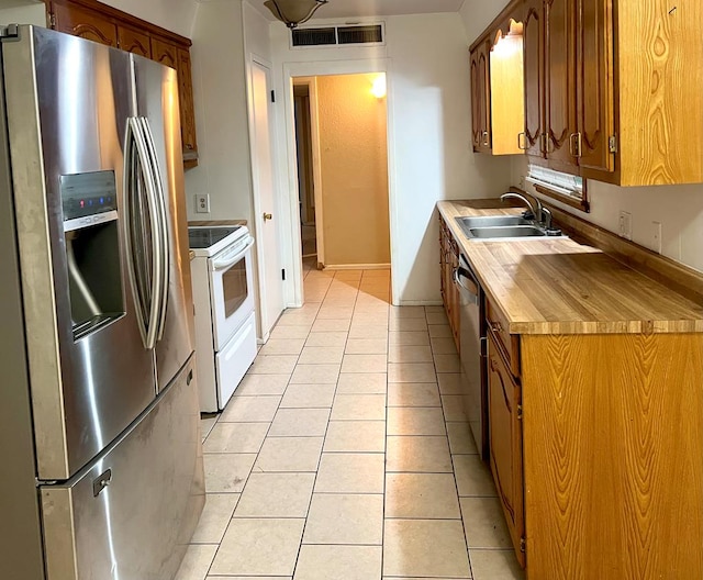 kitchen with sink, light tile patterned flooring, and appliances with stainless steel finishes